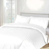 White striped bedding set on a bed with a neutral headboard.