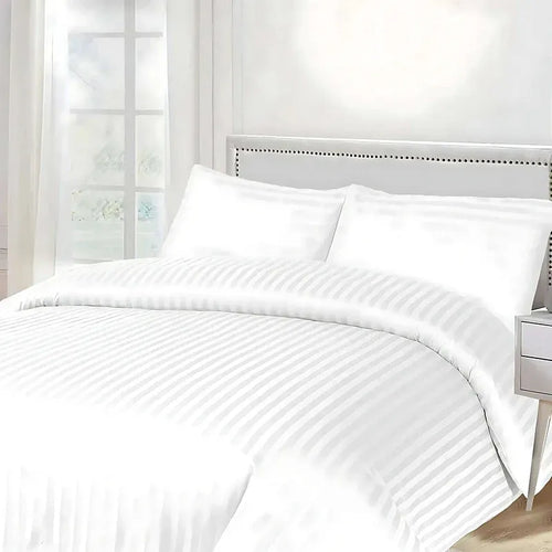 White striped bedding set on a bed with a neutral headboard.
