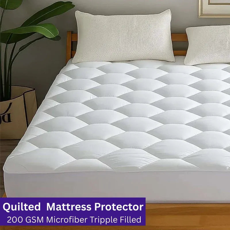 Quilted mattress protector on a bed with pillows and a plant in the background
