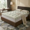 Mattress topper on a bed in a bedroom setting with a lamp and table.