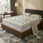 Mattress topper on a bed in a bedroom setting with a lamp and table.