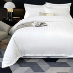 White bedding set on a bed with a magazine, in a bedroom setting.