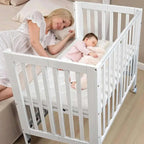 Woman lying on a bed next to a baby in a white crib.