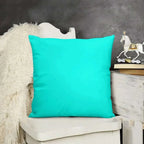 Turquoise pillow on a chair with a dark gray wall and decorative items in the background