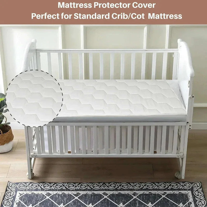 White crib with mattress protector cover on a wooden floor.