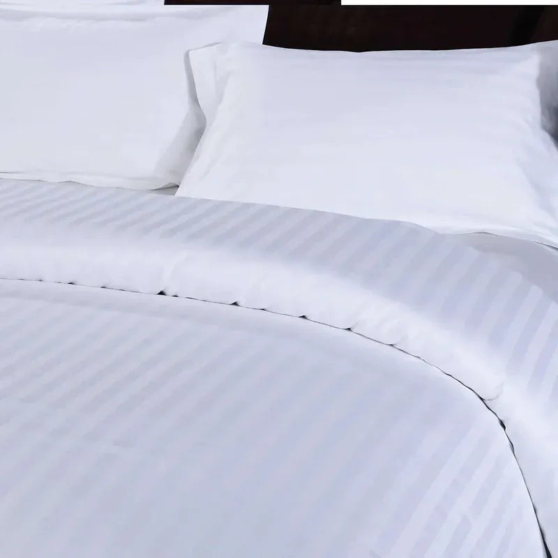 Close-up of white striped bedding with a dark headboard.