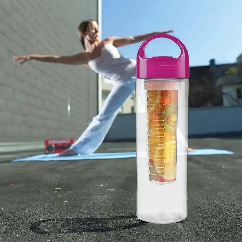 Clear water bottle with colorful fruit infuser on a yoga mat outdoors