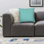 Gray sofa with a turquoise pillow and white fur pillow in a living room setting.