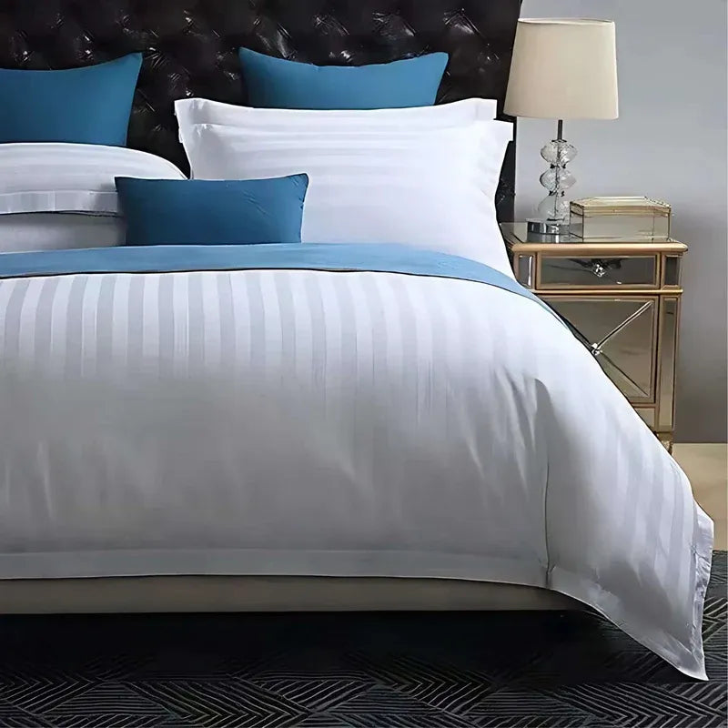 Neatly made bed with white and blue bedding in a bedroom setting.