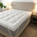 Mattress topper on a bed in a bedroom setting with lamps and plants.
