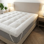 Mattress topper on a bed in a bedroom setting with lamps and plants.