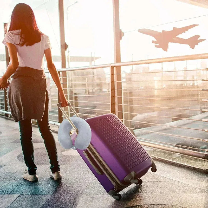 Person pulling a purple suitcase at an airport with a sunset in the background
