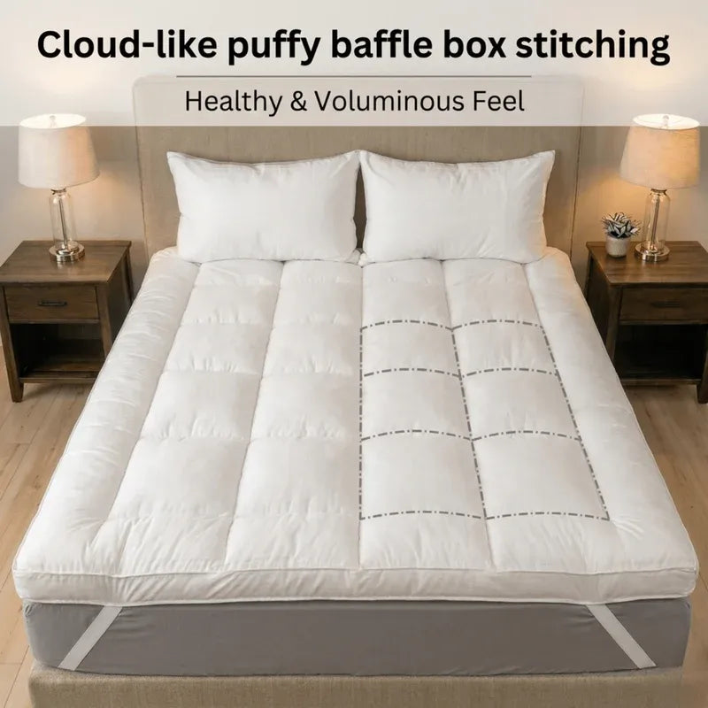 White mattress topper with puffy baffle box stitching on a bed in a bedroom setting.
