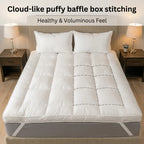 White mattress topper with puffy baffle box stitching on a bed in a bedroom setting.