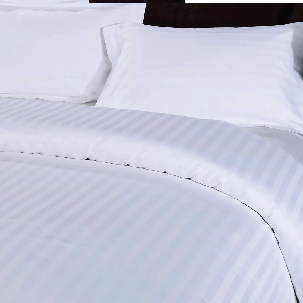 Close-up of white striped bedding with a dark headboard.