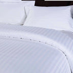 Close-up of white striped bedding with a dark headboard.