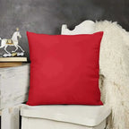 Red pillow on a white chair with a dark gray wall and decorative items in the background