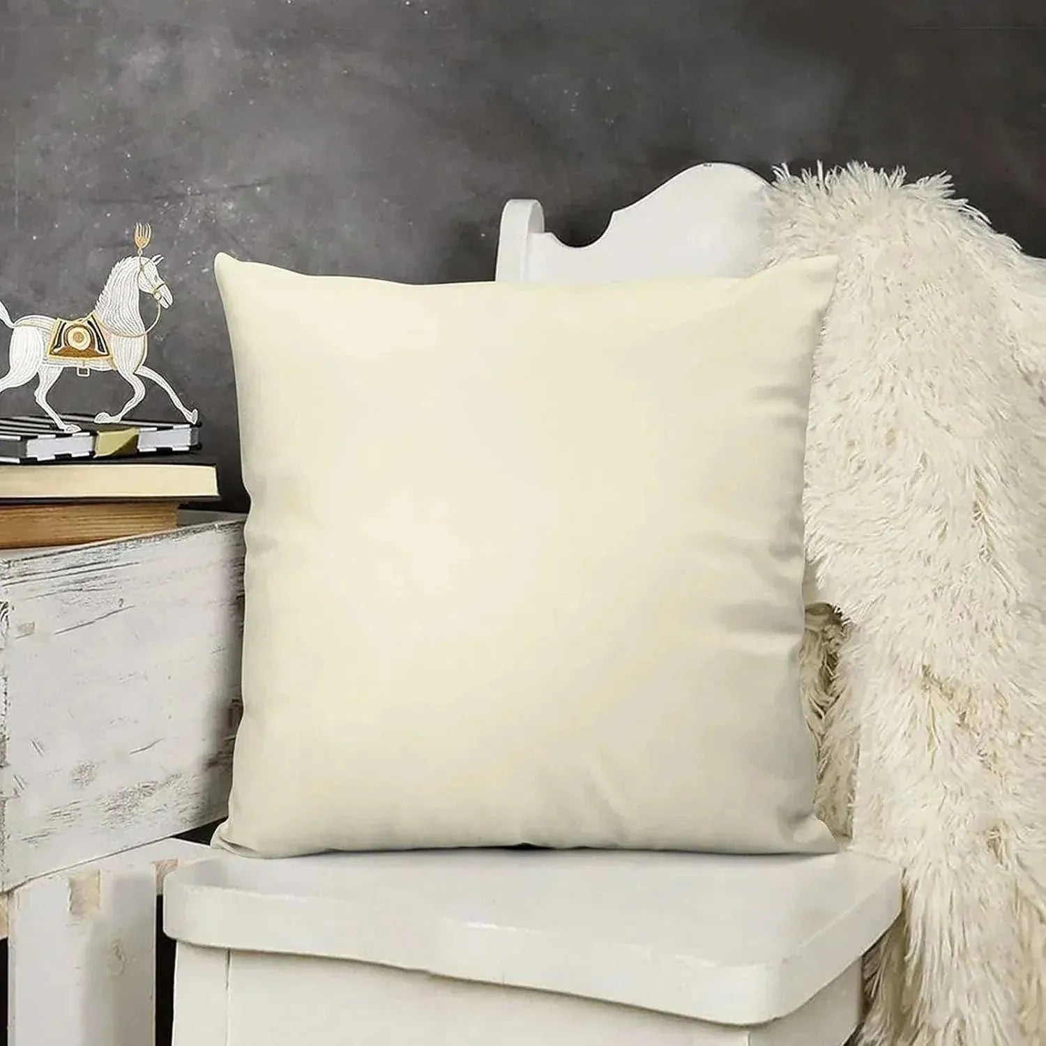 Beige pillow on a white chair with a dark gray wall and decorative items in the background