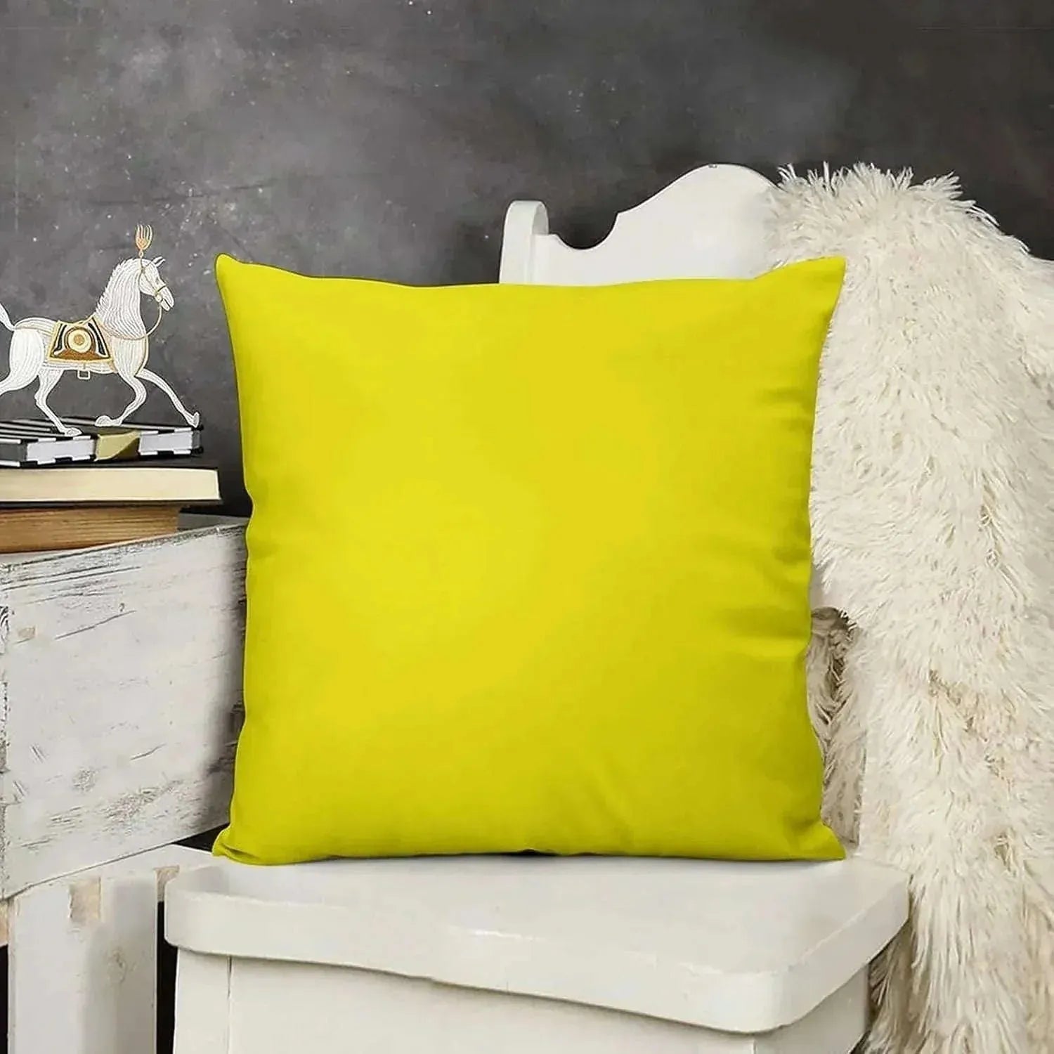 Yellow pillow on a white chair with a dark gray wall in the background