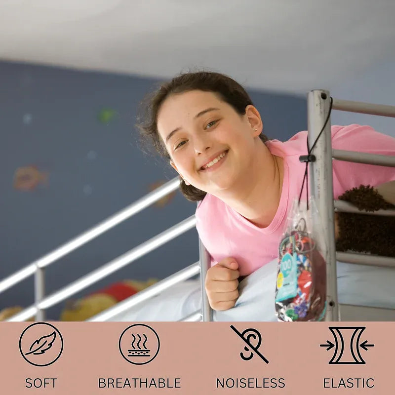 A smiling girl in a pink shirt leans over a bunk bed holding a colorful hanging bag. A pink banner at the bottom lists product features: SOFT, BREATHABLE, NOISELESS, and ELASTIC.