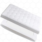 A white contoured mattress topper with a quilted zigzag pattern on top and a perforated inner layer, shown floating against a white background with a faint hexagonal grid pattern.