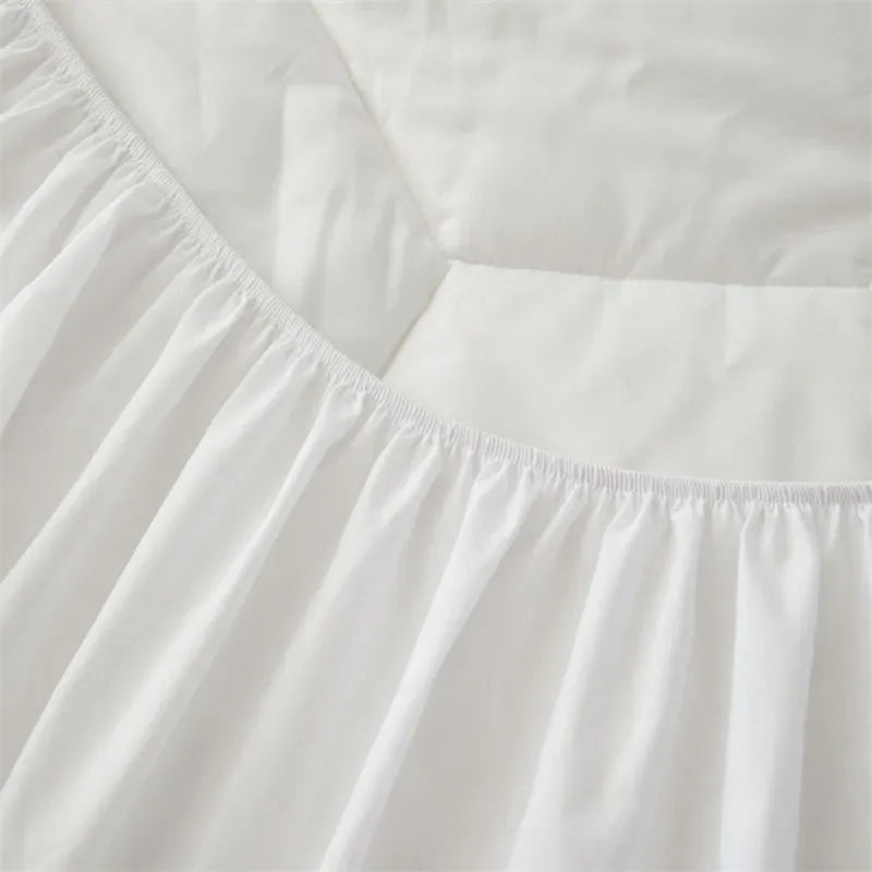 Close-up of a white bed sheet or duvet cover with a gathered elasticized corner and smooth folded fabric.