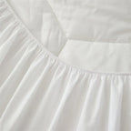 Close-up of a white bed sheet or duvet cover with a gathered elasticized corner and smooth folded fabric.