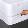 Person zipping up a white mattress protector on a bed.